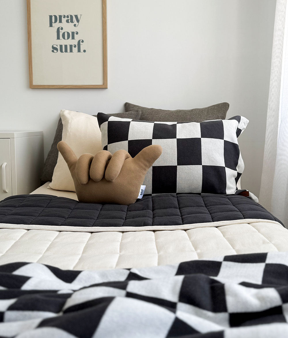 Charoal and Ivory checker duvet cover, natural quilt, and matching cushions with a shakabra shaped cushion and 'pray for surf' printed frame