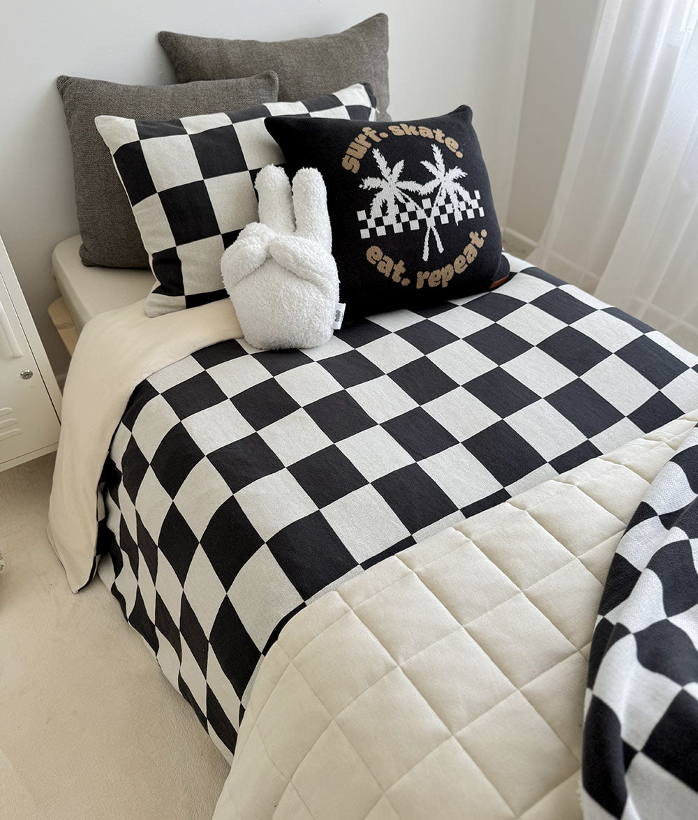 Bed with black and white checkered comforter and pillows in a bedroom setting.
