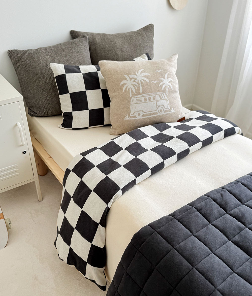 Bed with checkered blanket and decorative pillows in a bedroom setting