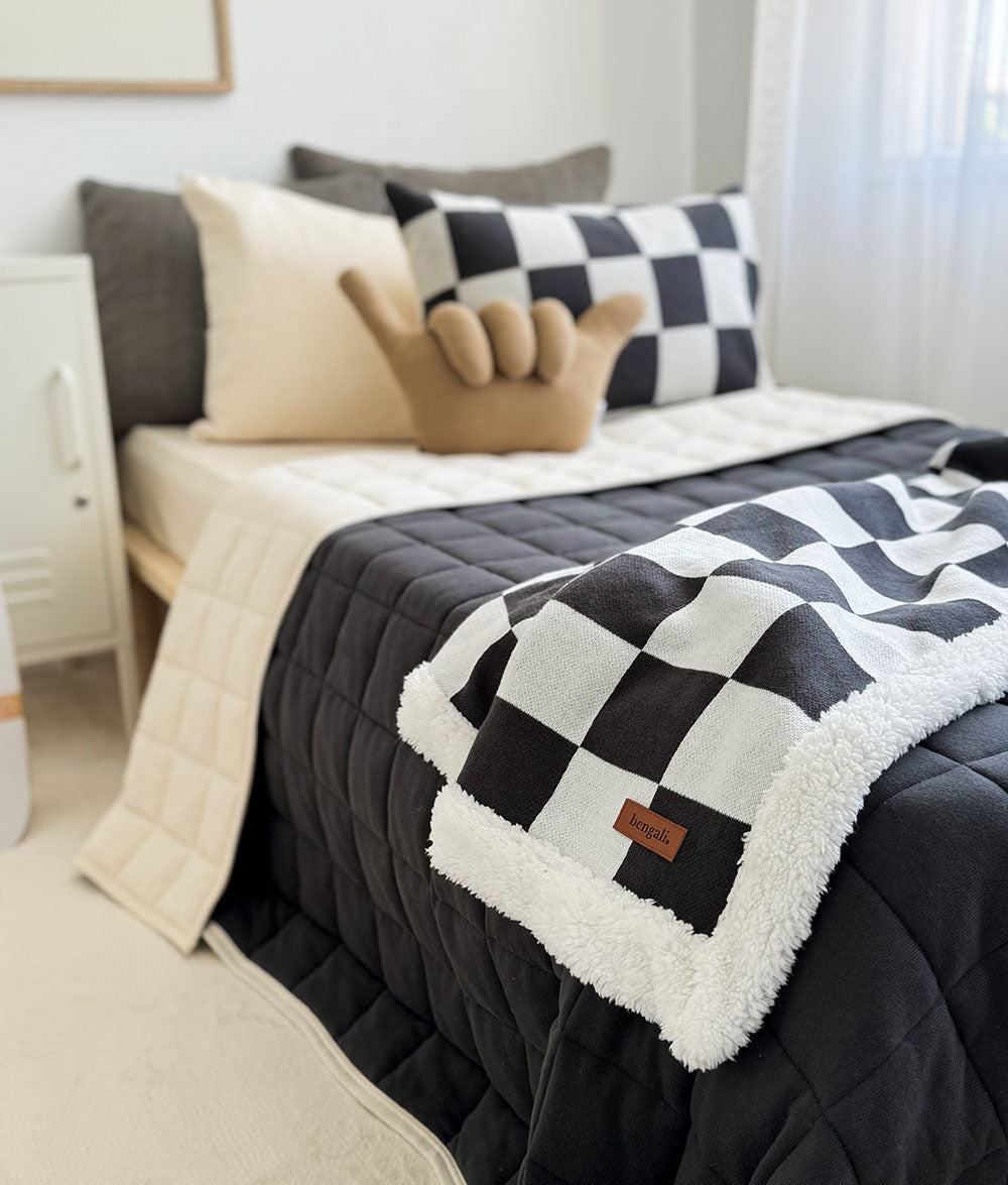 Bed with checkered blanket and pillows in a bedroom setting