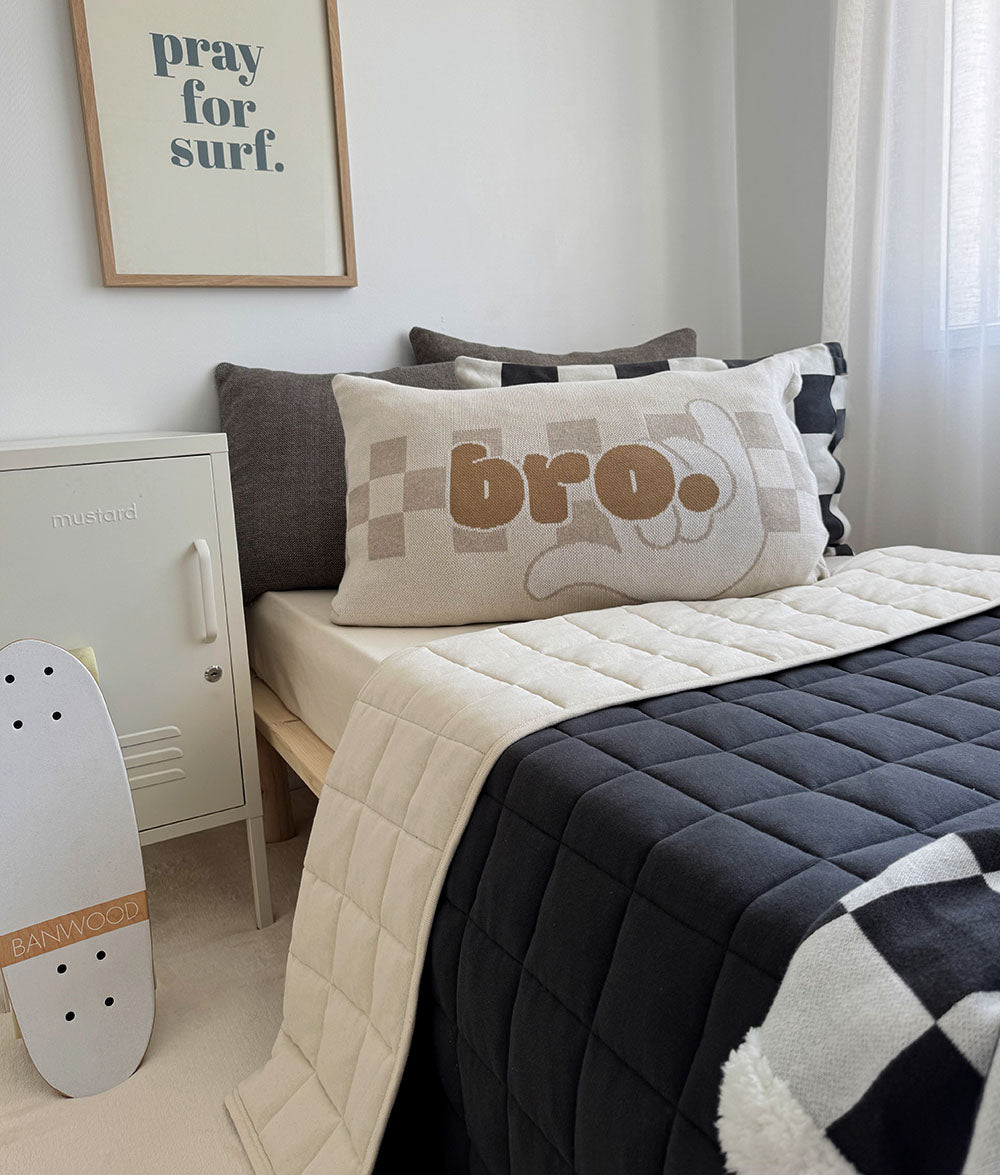 Bedroom with a bed featuring a 'bro.' pillow, a skateboard, and a framed picture on the wall.