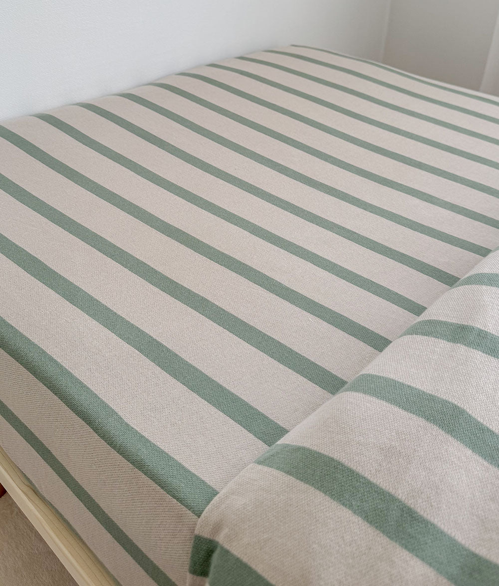 Striped green and beige mattress cover on a bed.