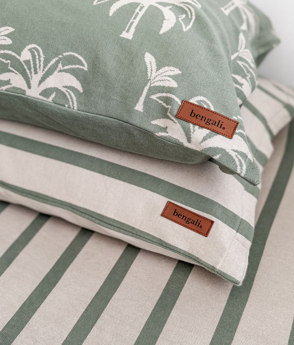 Two pillows with green and white patterns and 'bengali' branding on a bed.