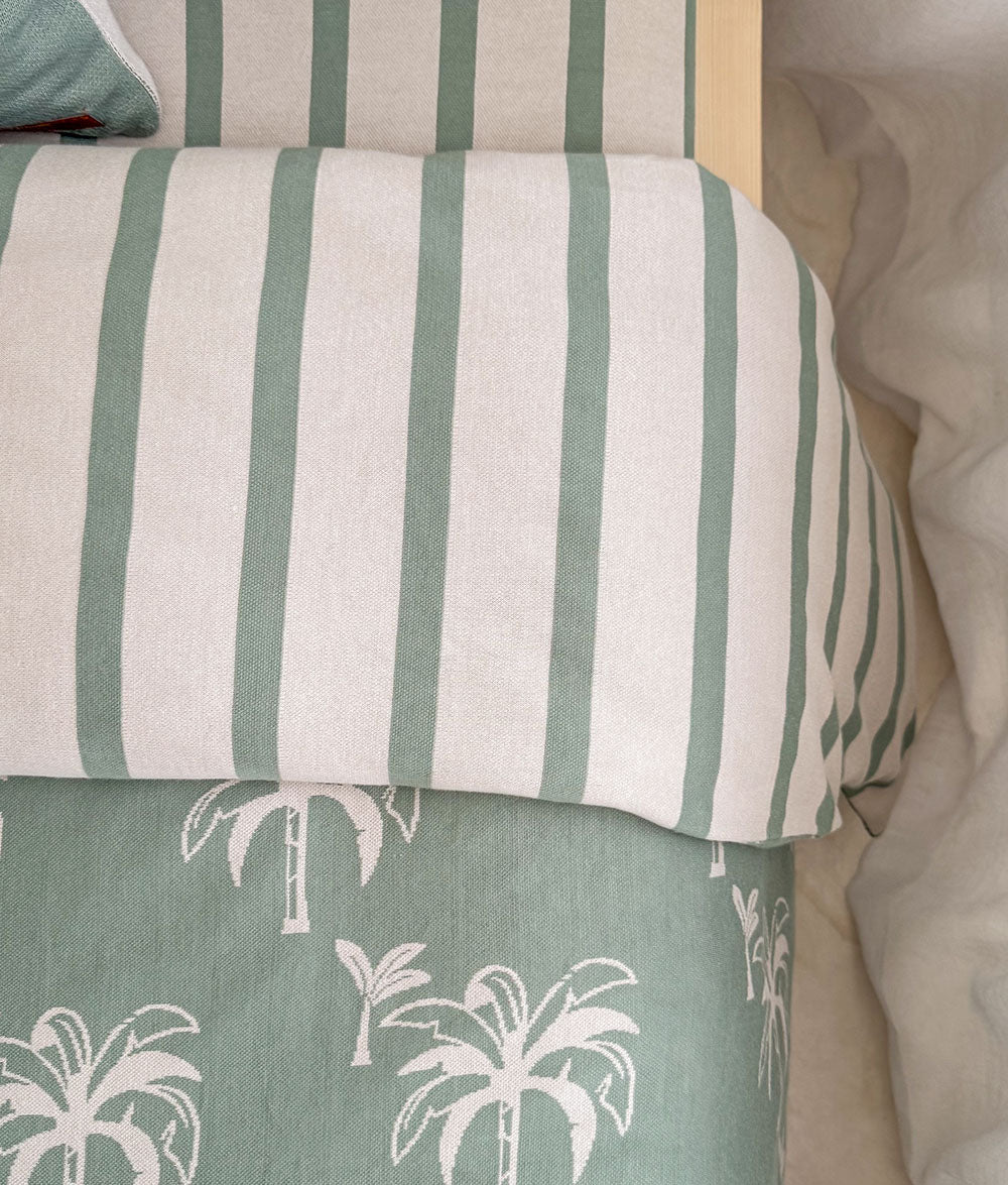 Striped pillow with green and white stripes on a textured surface