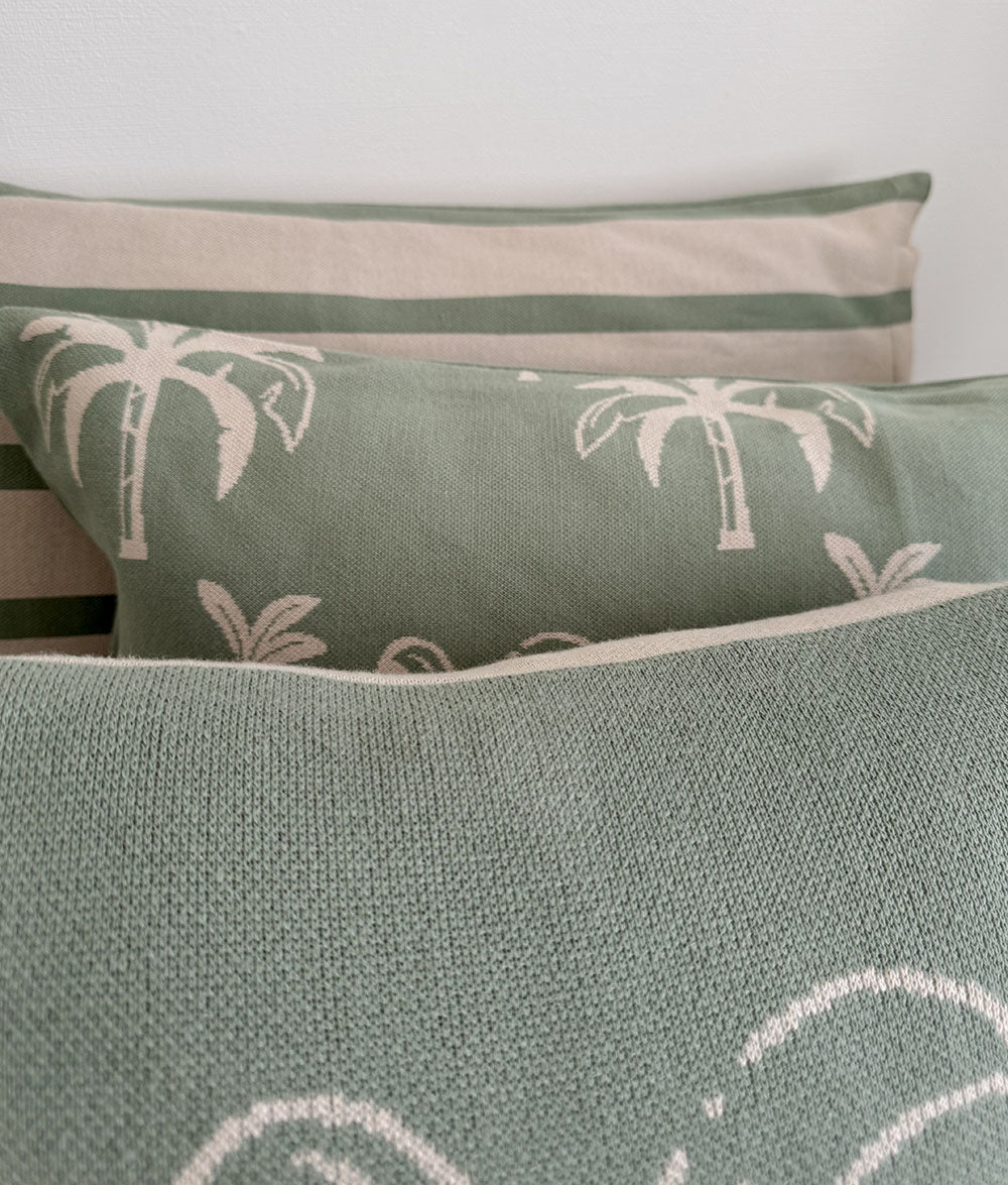 Green pillows with palm tree patterns on a neutral background