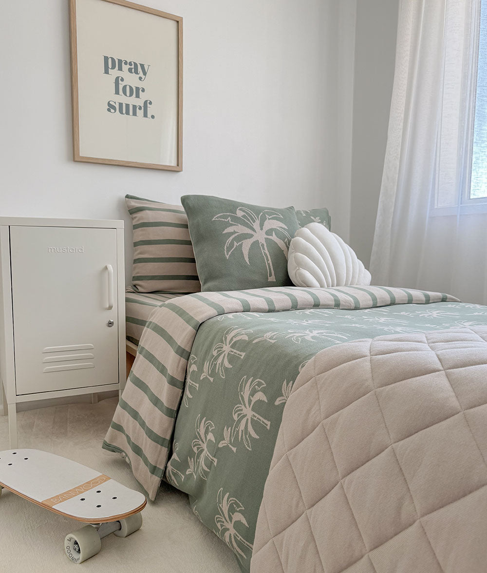 Bedroom with green and beige bedding, a skateboard, and a framed quote on the wall.