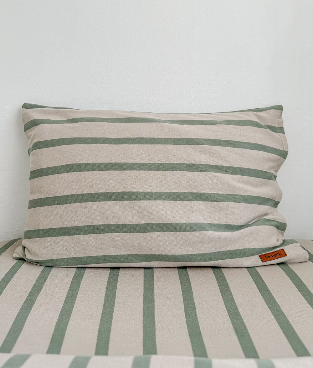 Striped pillow and bedding with a visible brand label on a plain background