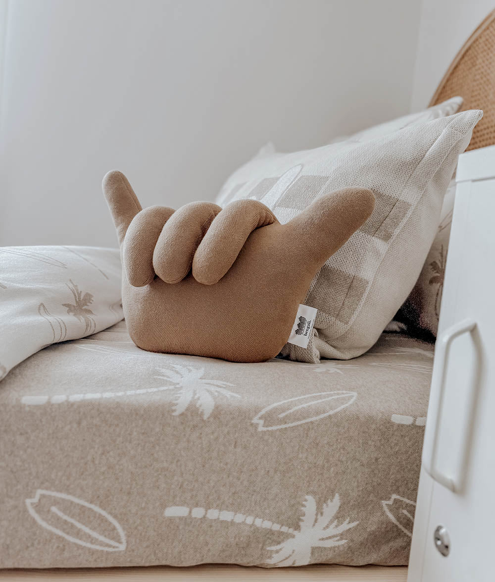 Brown hand-shaped pillow on a beige couch with white cushions.
