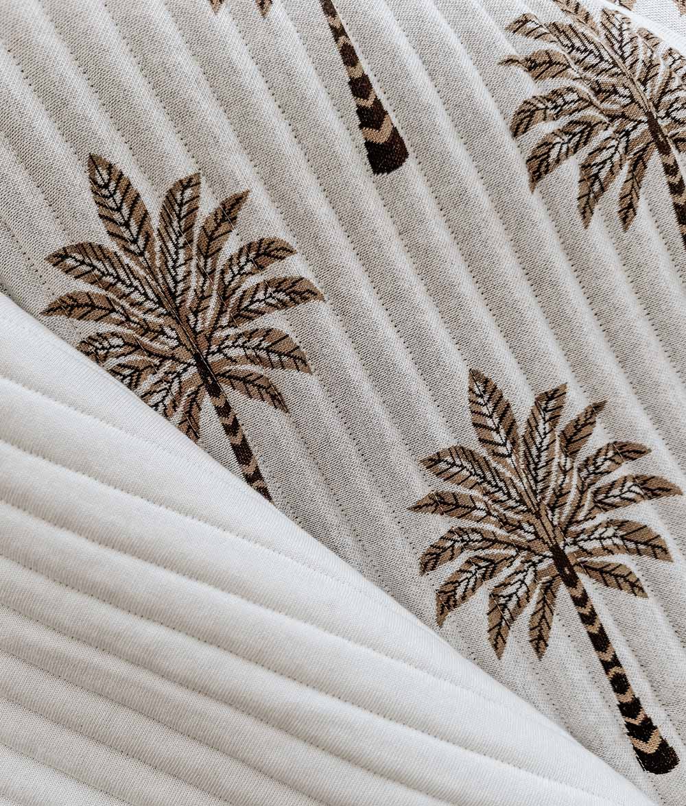 Close-up of the Khaki Sundown reversible quilt with chocolate and khaki palm tree print.