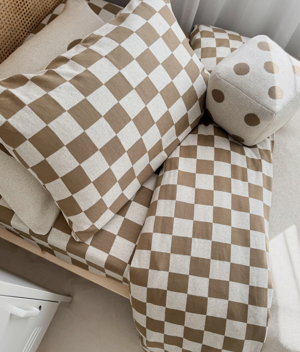 Close-up of the Khaki Gingham duvet cover layered with matching bedding.