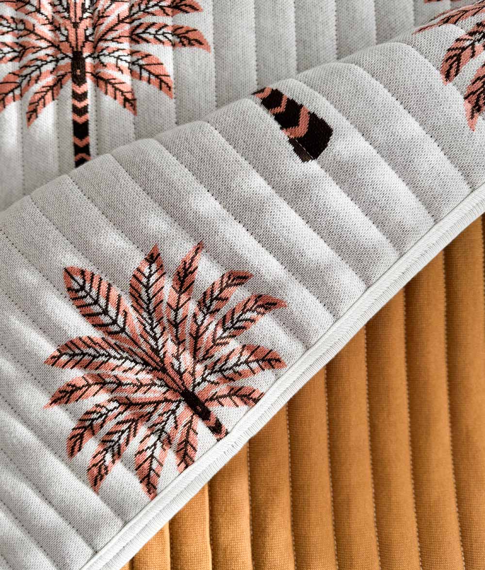Close-up of the Peach Sundown reversible quilt with plain tobacco reverse.