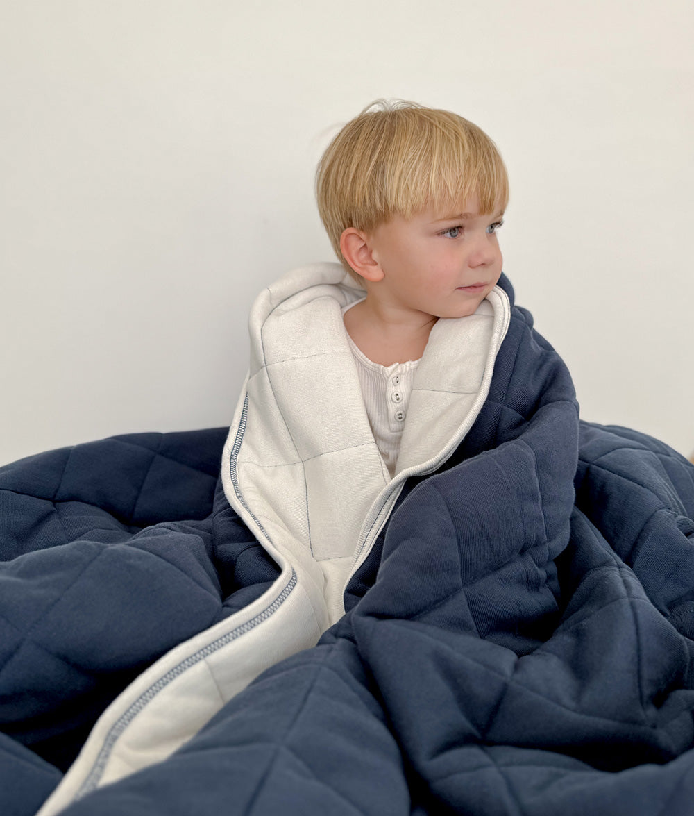 Child wrapped in the Tidal Blue quilt.