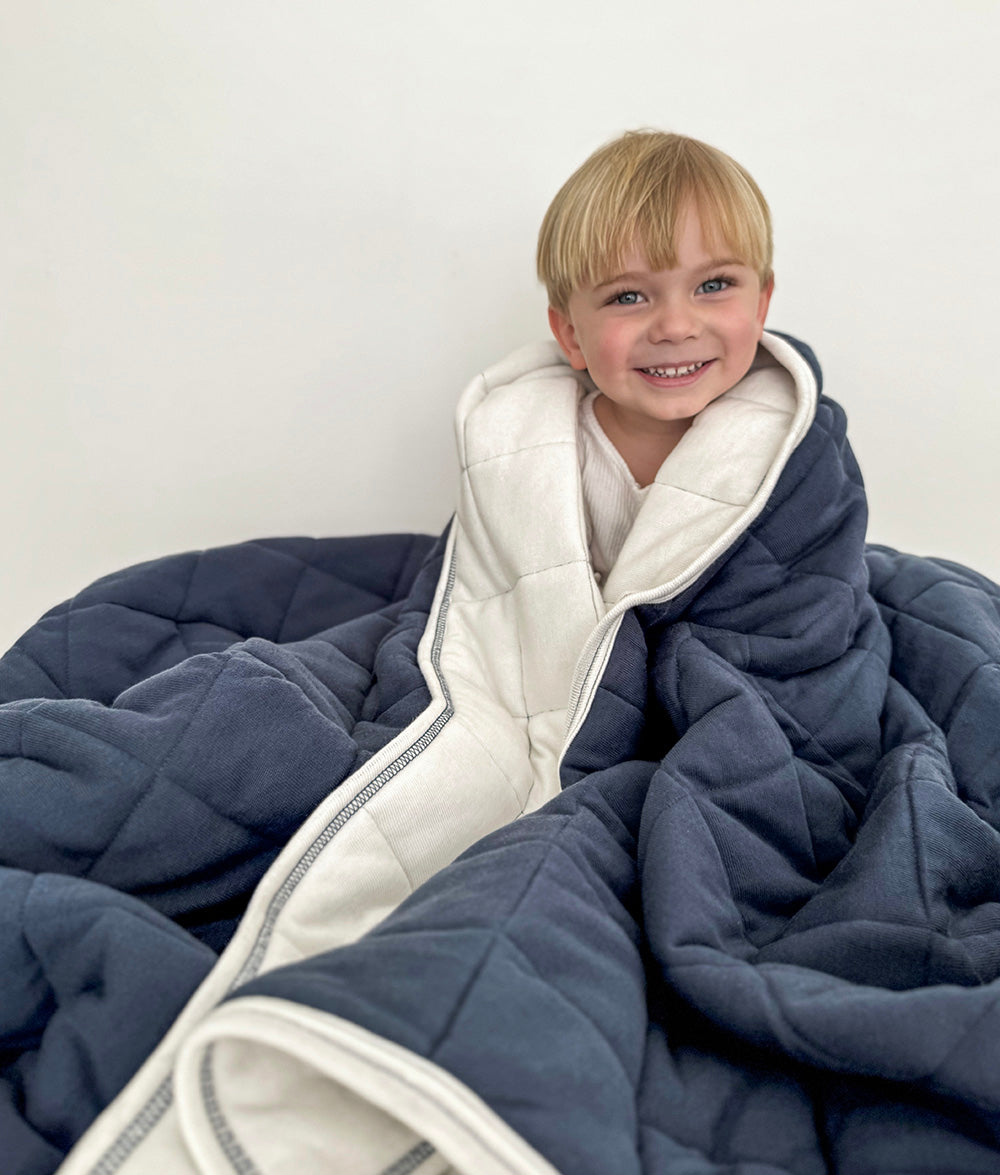 Child wrapped in the Tidal Blue quilt.