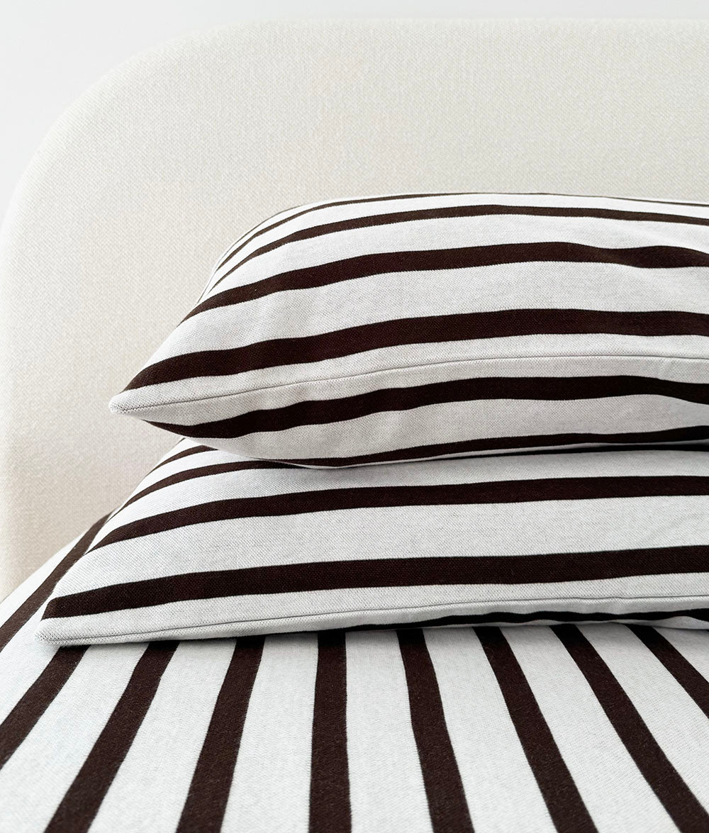 Sundown Stripe reversible pillowcases styled on a queen bed.