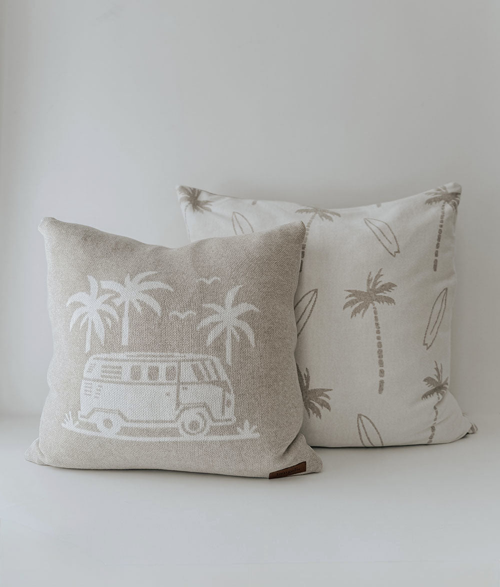 Two decorative pillows with vintage van and palm tree designs on a plain background