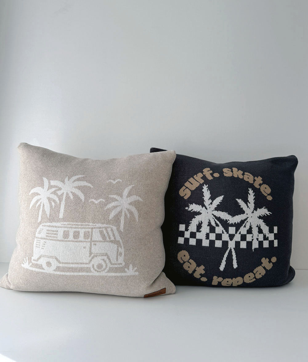 Two decorative pillows with beach-themed designs on a plain background