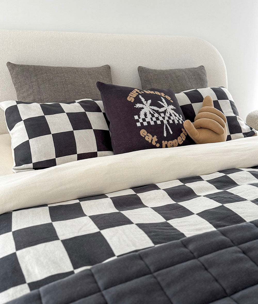 Bed with checkered bedding and decorative pillows on a white background