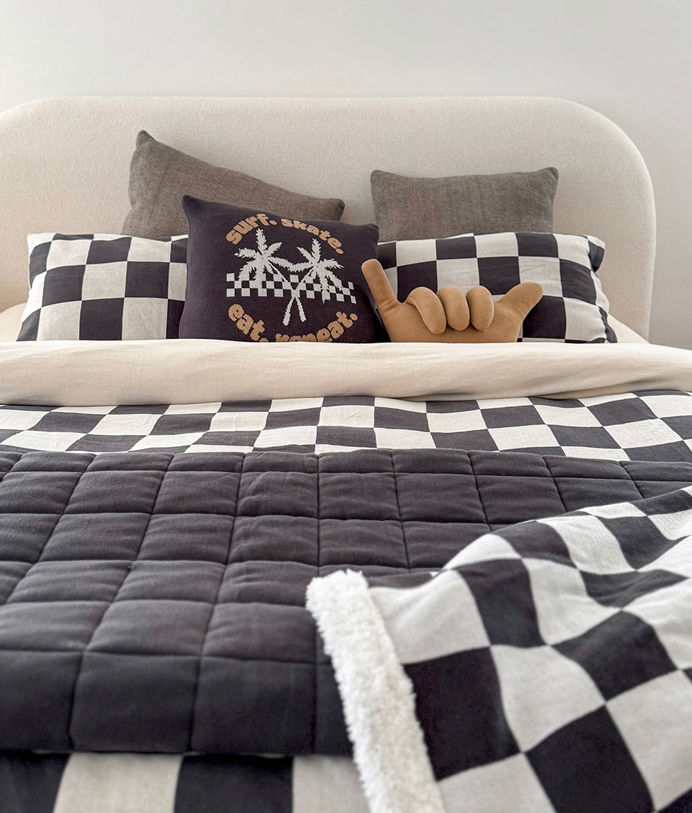 Bed with checkered bedding and decorative pillows in a bedroom setting