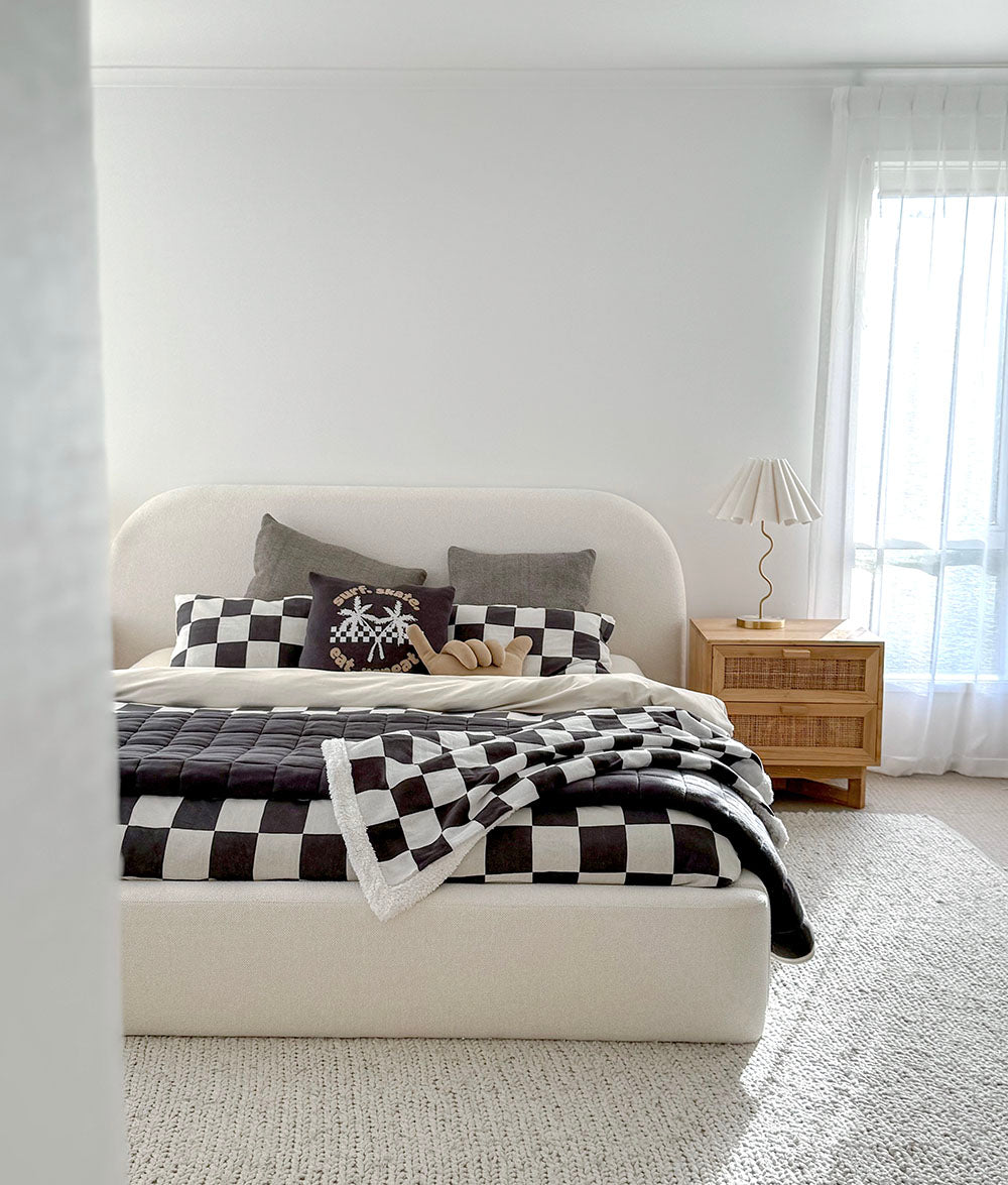 Bedroom with a bed featuring checkered bedding and pillows, a lamp, and a nightstand.