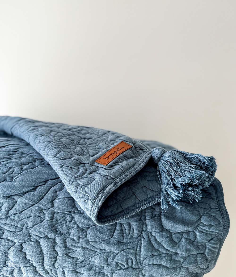 Blue textured blanket with a brand label on a light background