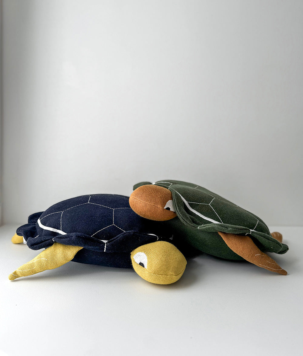 Two plush turtle toys on a white surface with a light gray background