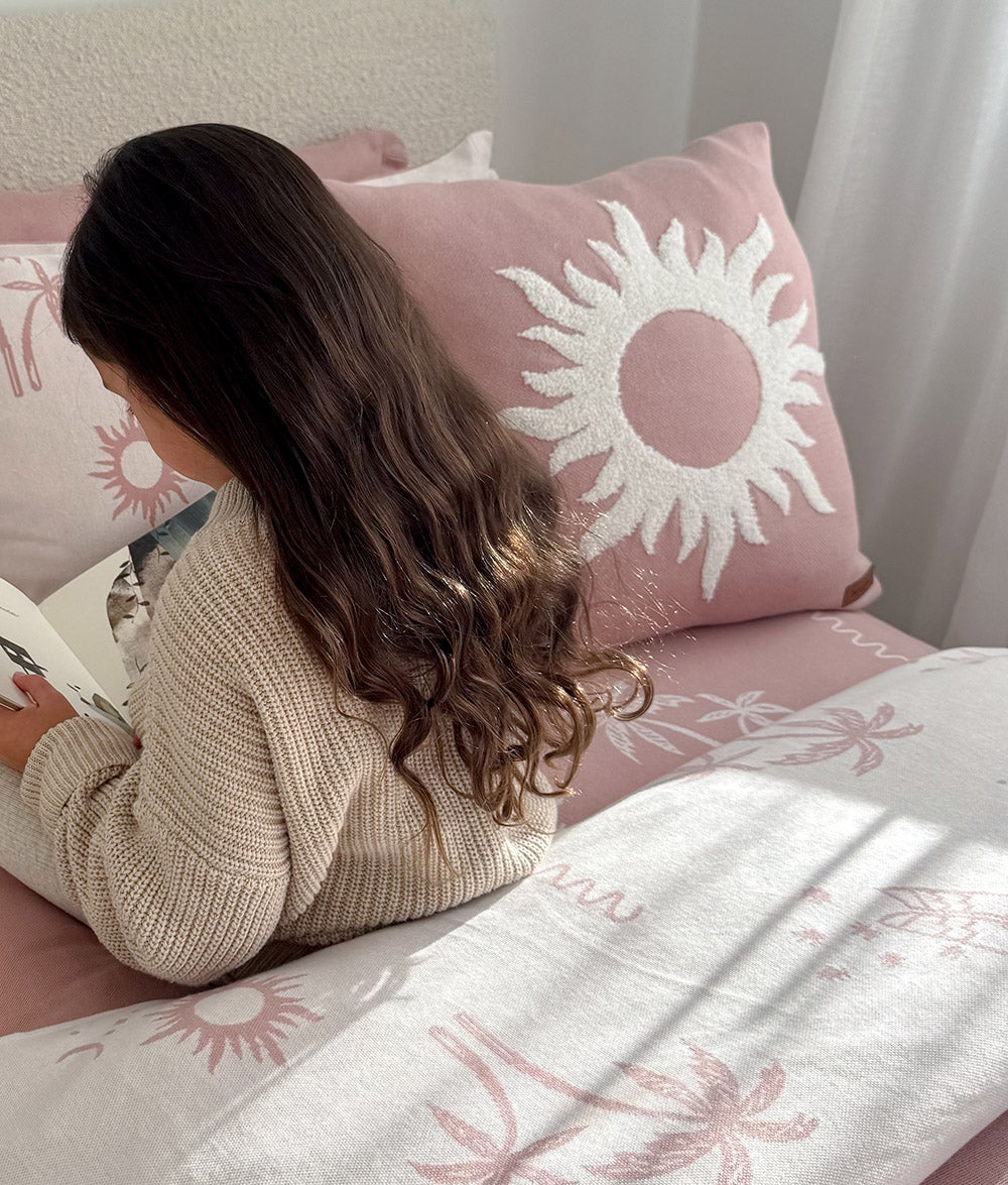 Pink Sol cushion cover styled on a child's bed.