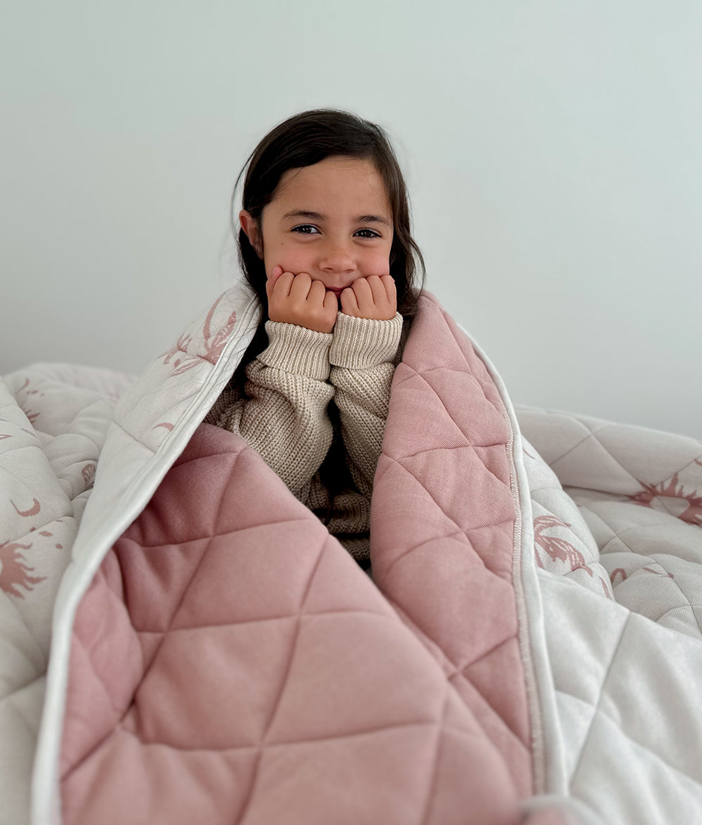 Child wrapped in the Sun Kissed reversible quilt.