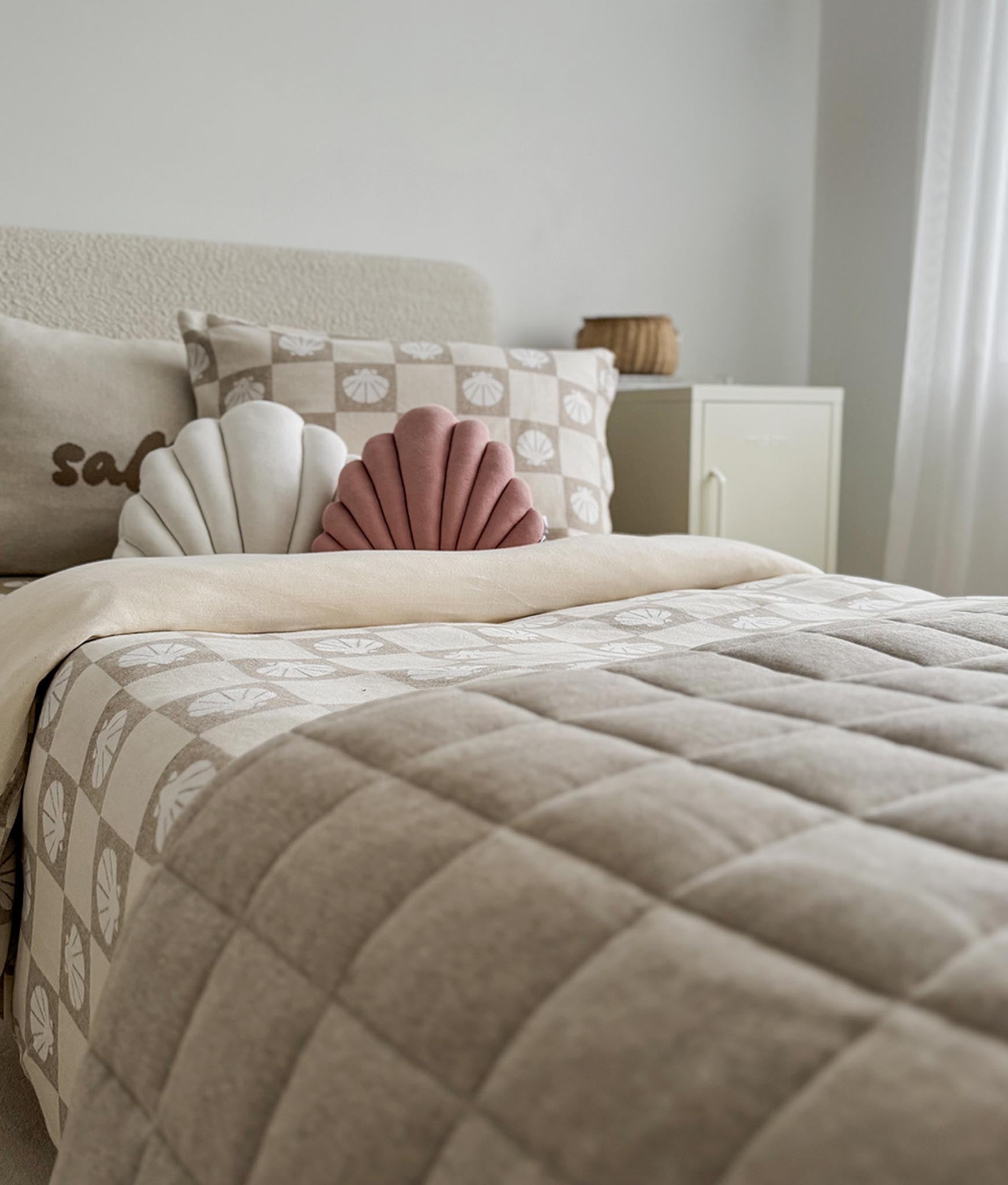 Neatly made bed with decorative pillows and a quilt in a bedroom setting.