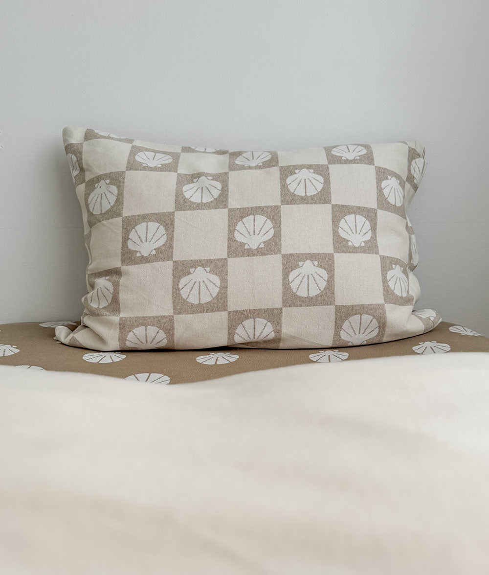 Checkered pillow with shell pattern on a bed