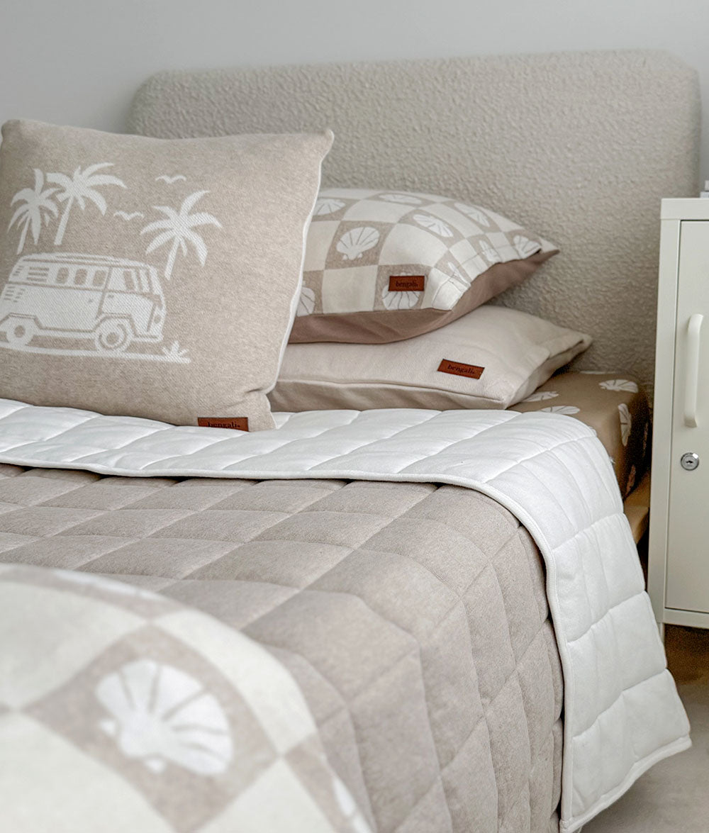 Neatly made bed with patterned pillows and quilt in a bedroom setting.