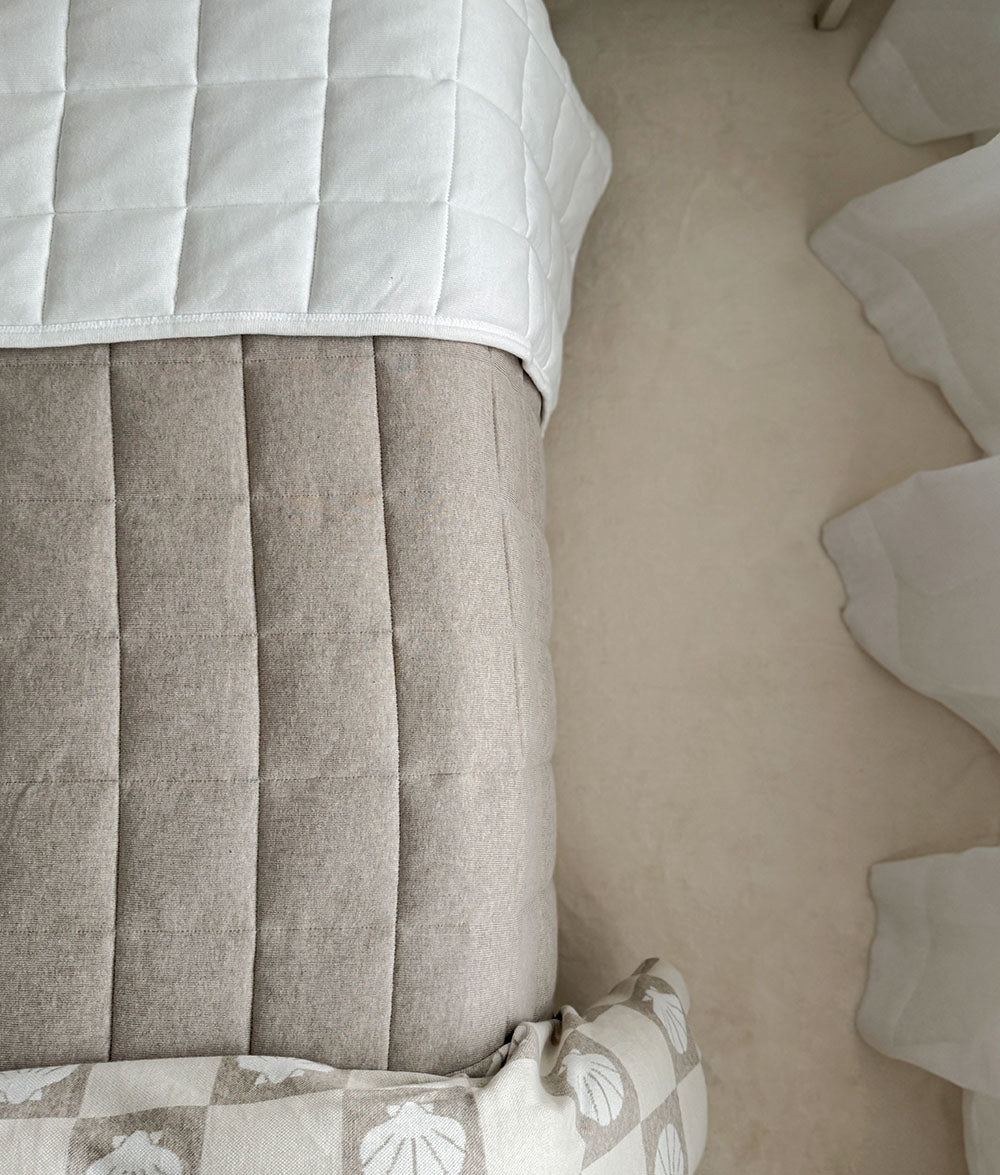 Close-up of a bed with gray headboard and white bedding