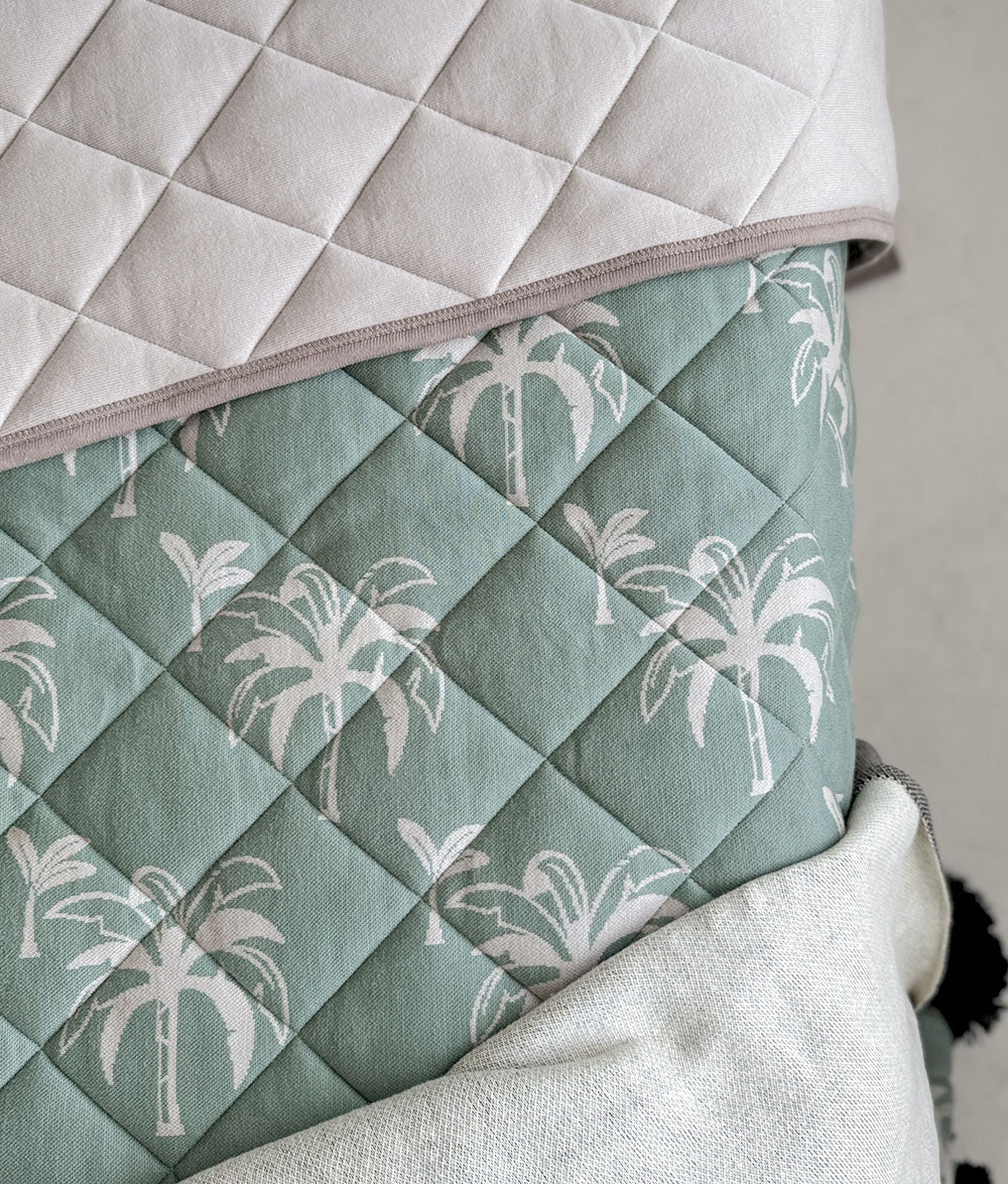 Quilted fabric with palm tree pattern on a neutral background