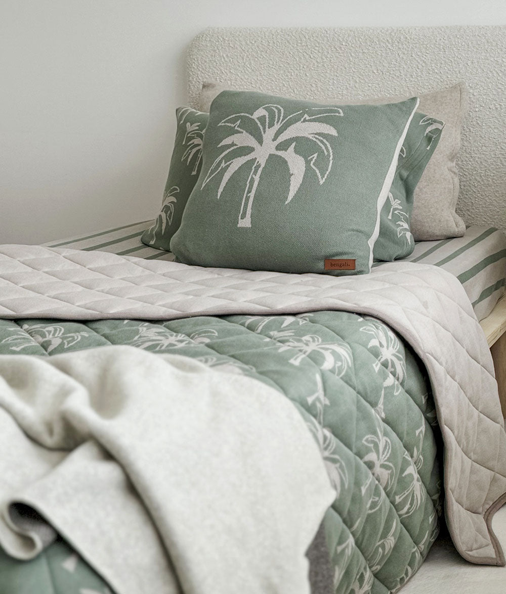Bed with green and beige bedding featuring palm tree design