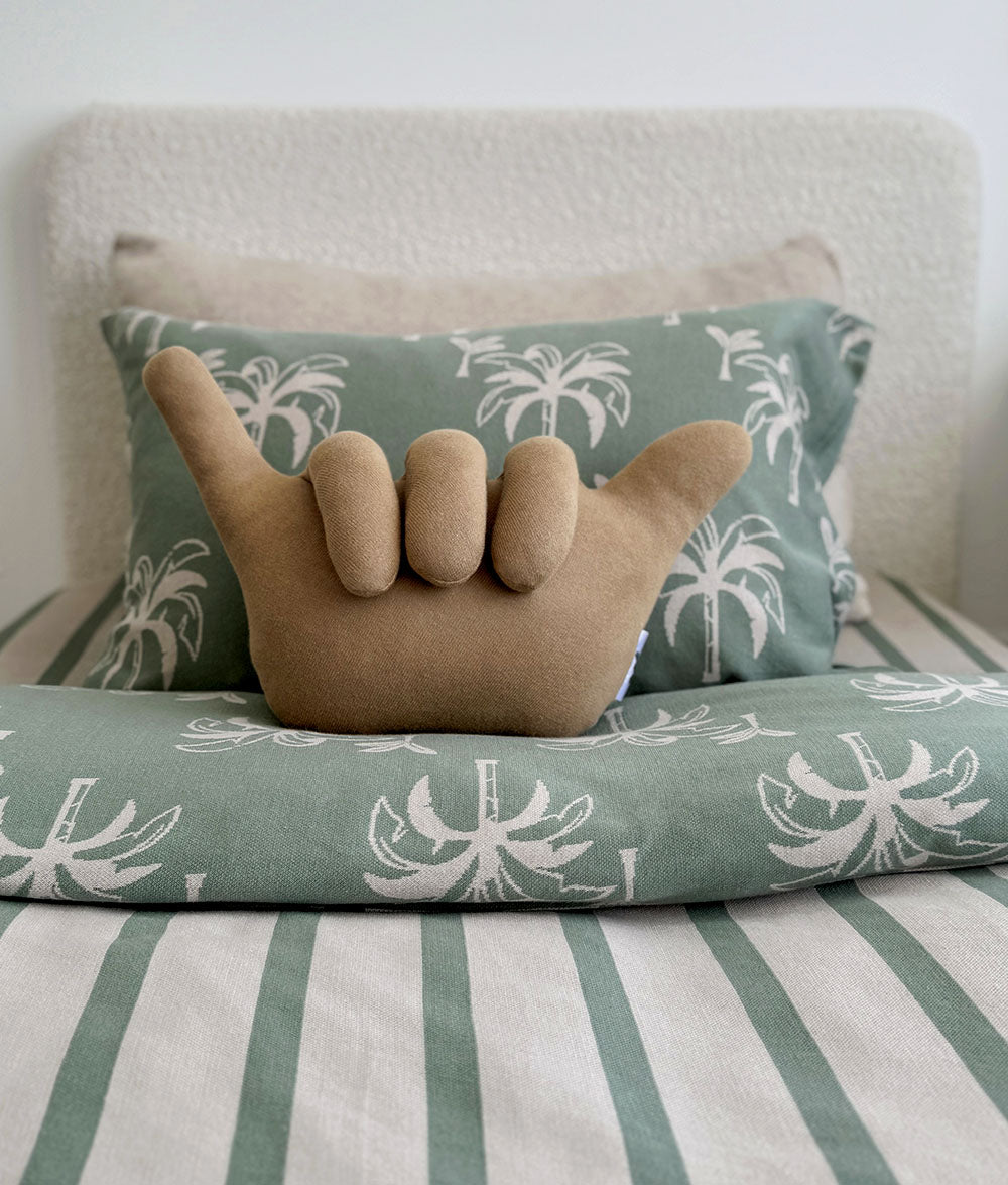 Decorative pillow with palm tree pattern on a striped bedspread