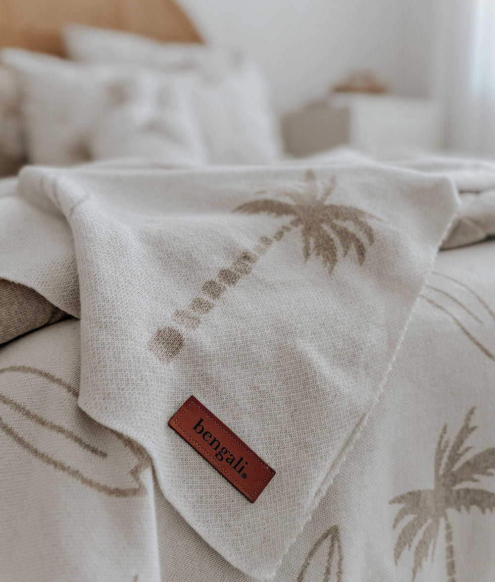 Textile with palm tree patterns and a 'bengal' label on a bed.