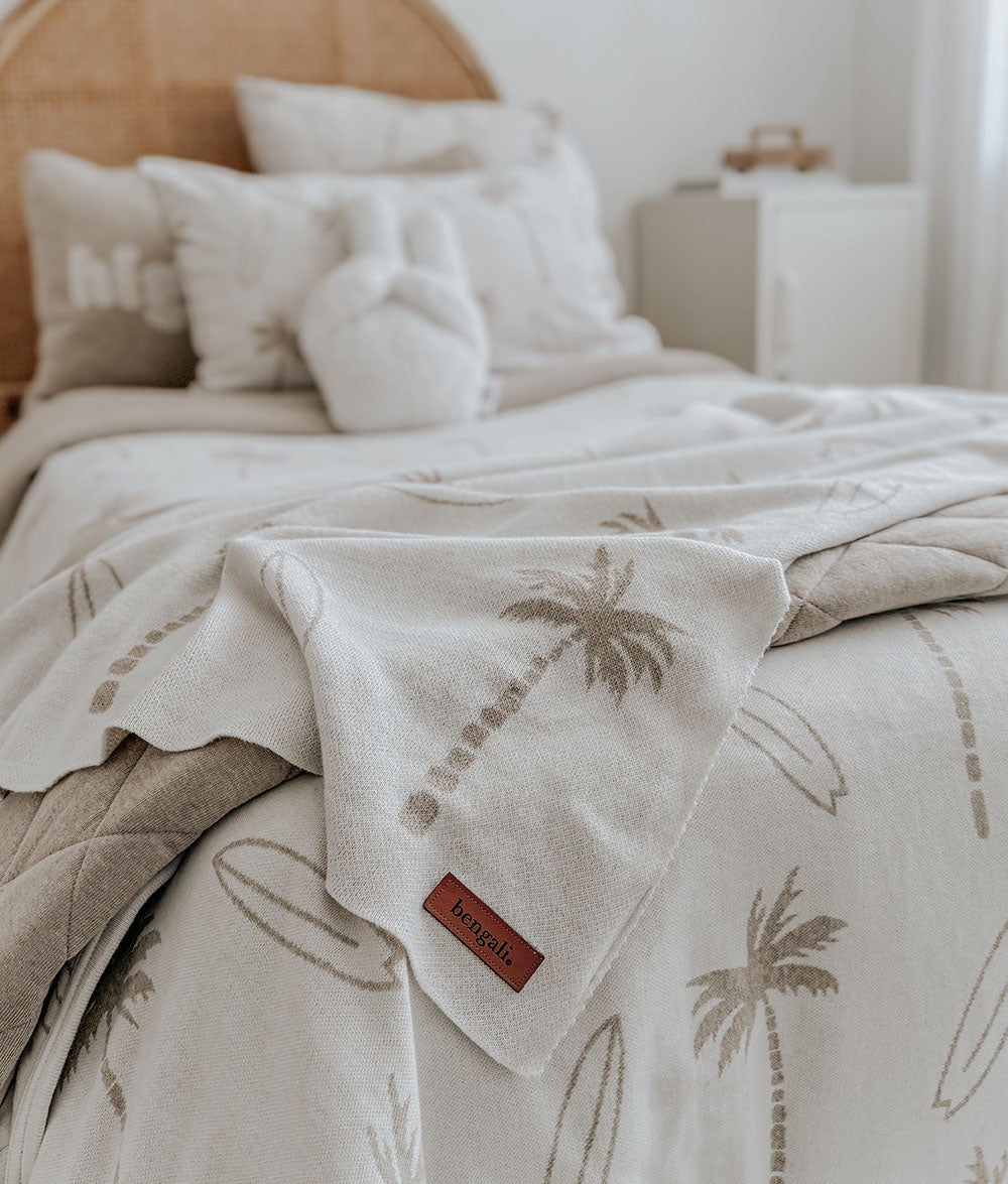 Beige quilt with palm tree pattern on a bed in a bedroom setting