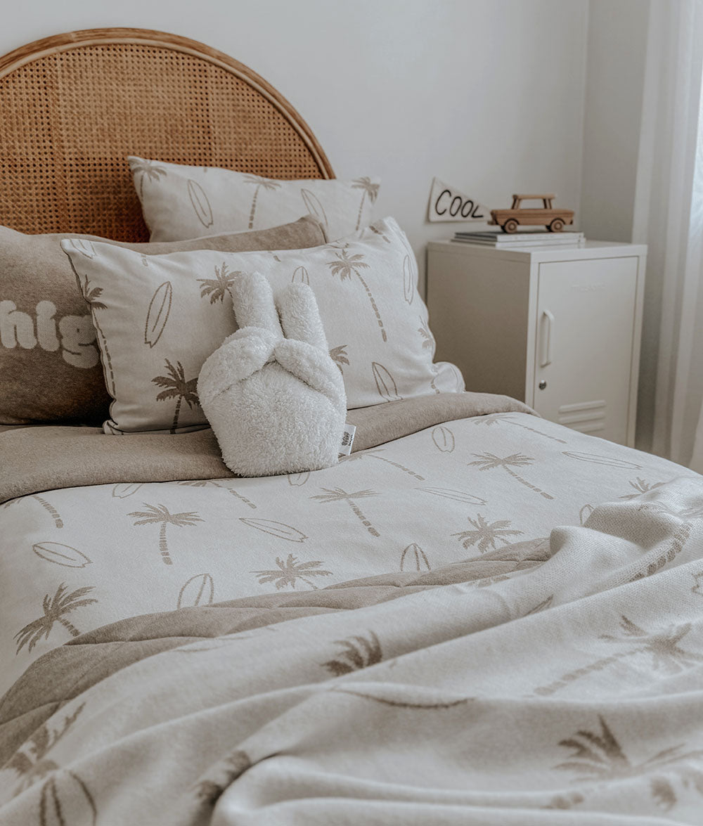 Neatly made bed with patterned bedding and pillows in a bedroom setting.