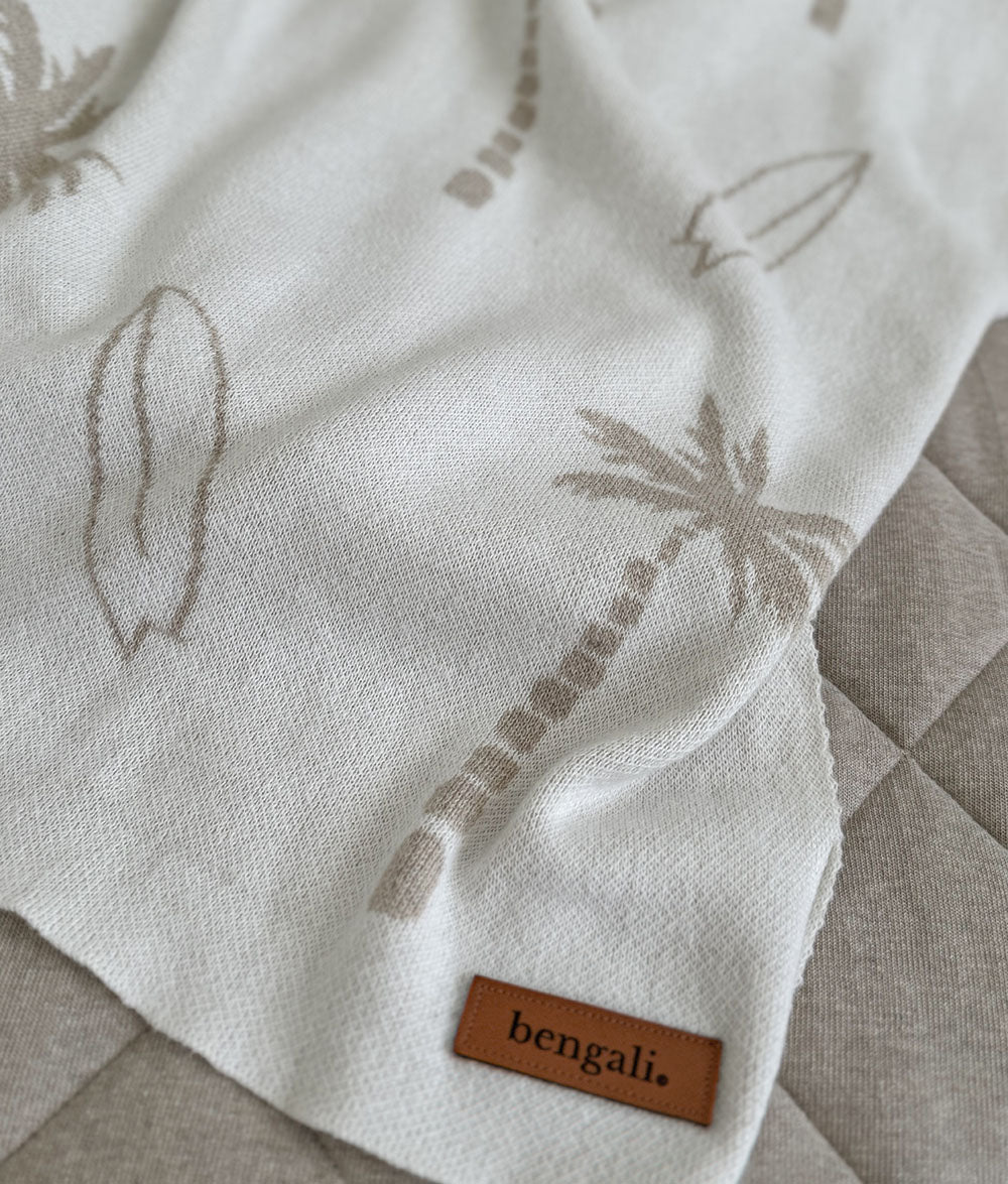Textured fabric with palm tree designs and a 'bengali' label on a checkered surface.
