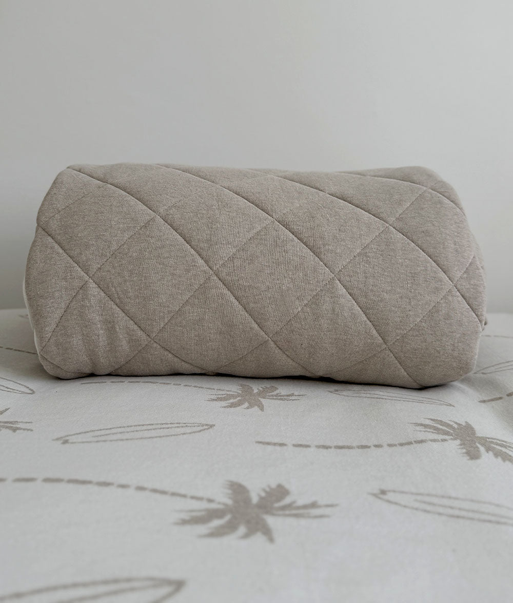 Quilted blanket on a bed with a palm tree pattern