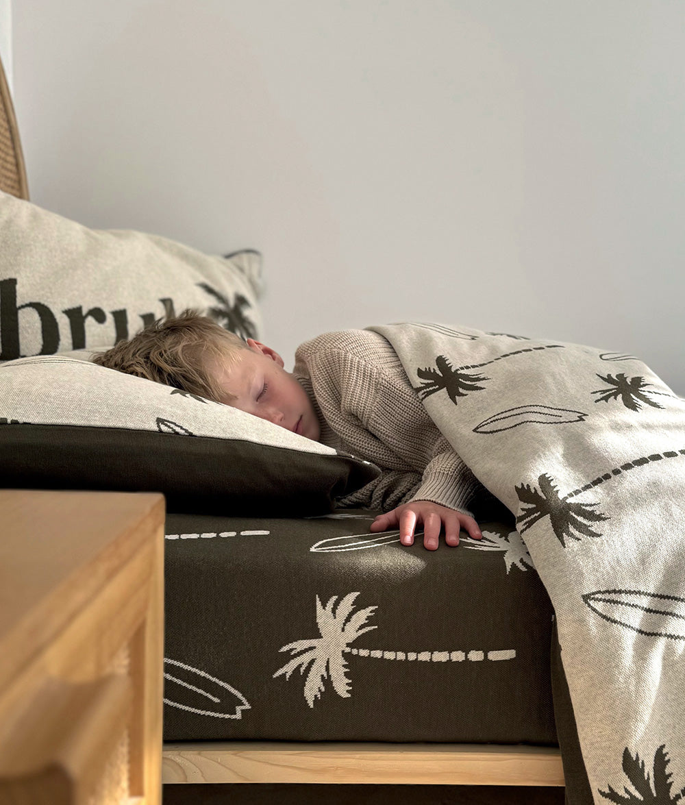 Child resting with the Olive & Natural Marle "bruh." reversible pillowcase.