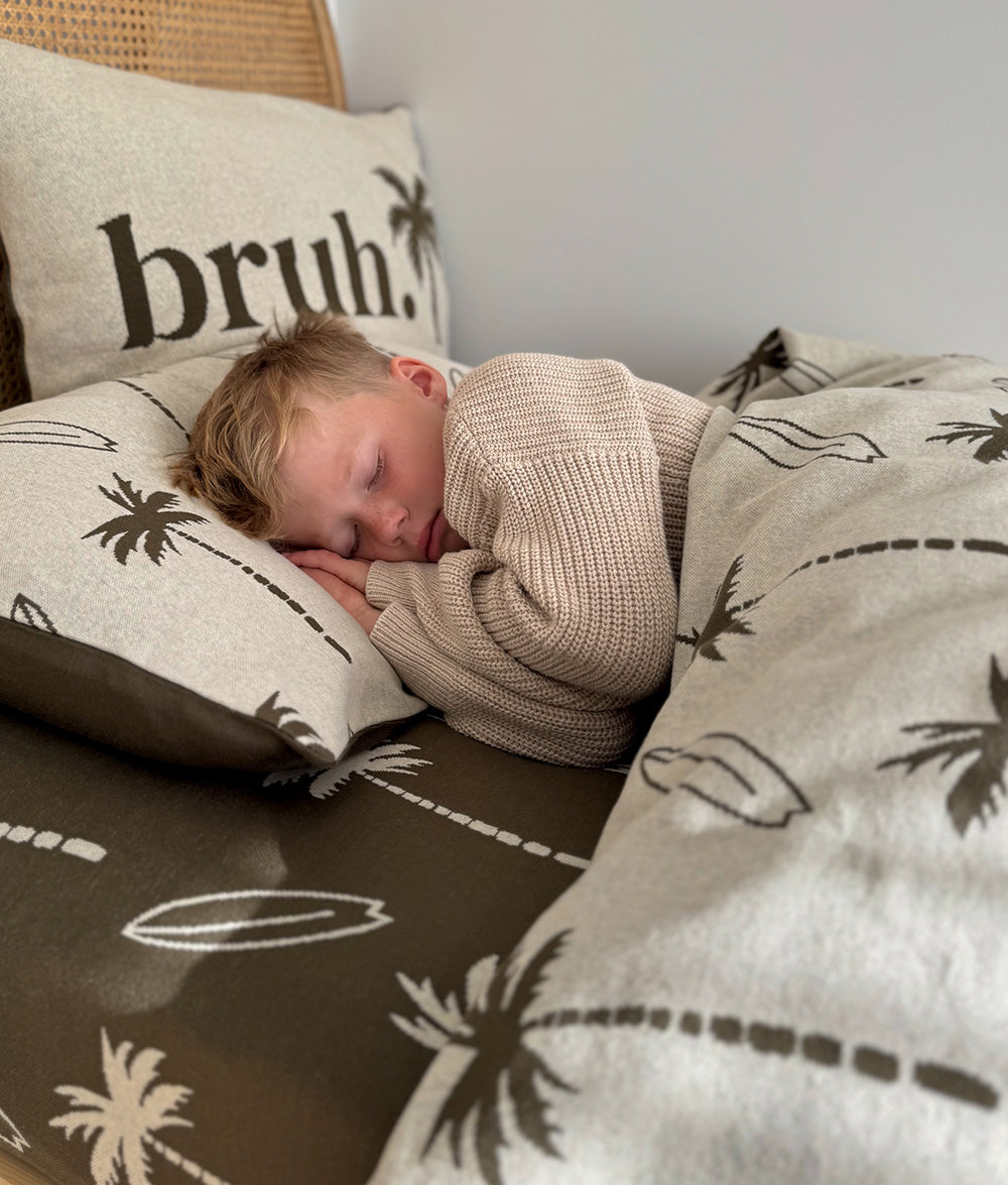 Child sleeping in Olive Surfing Palm bedding.