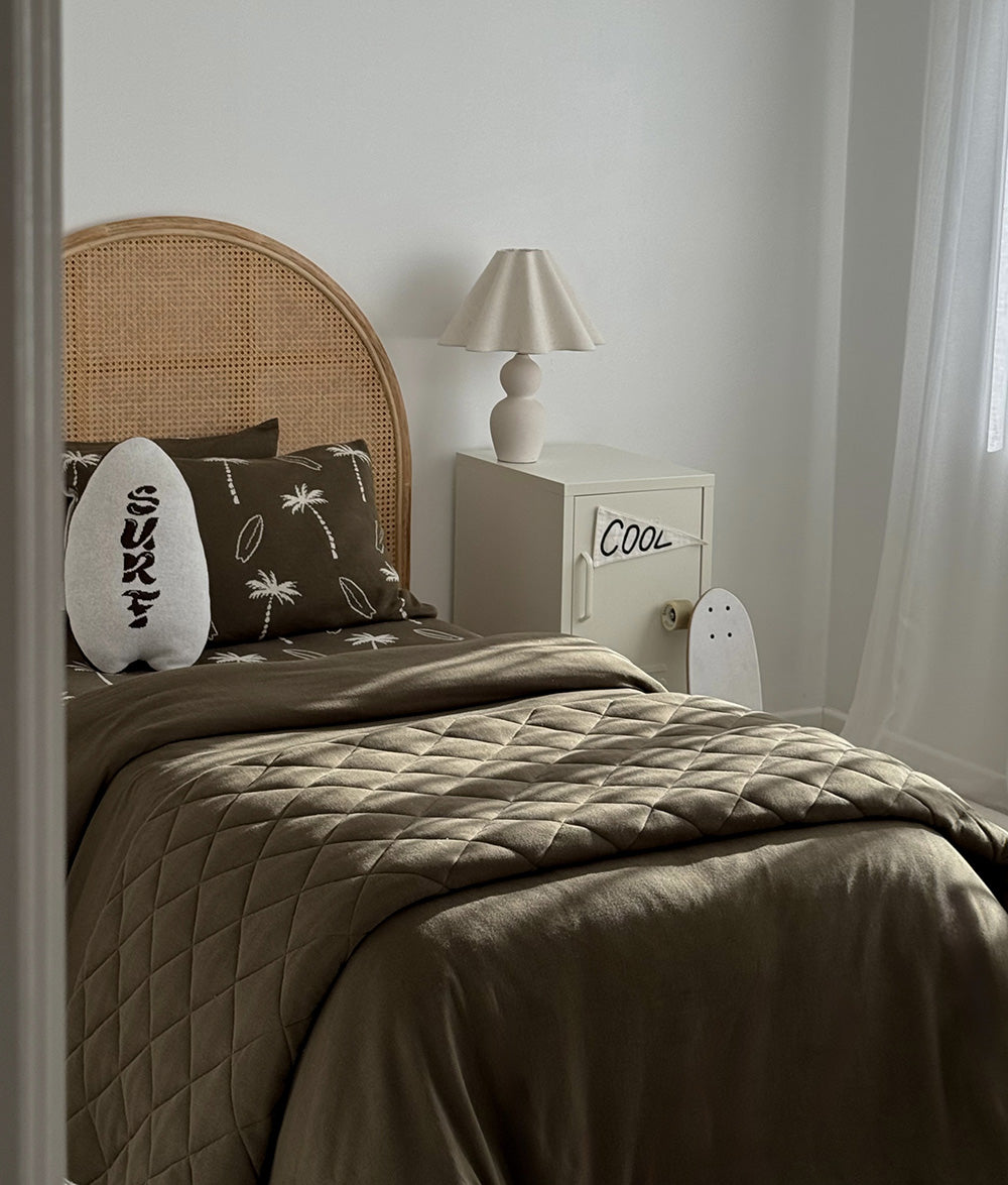Olive Surfing Palm jersey cotton bedding styled with matching cushions.
