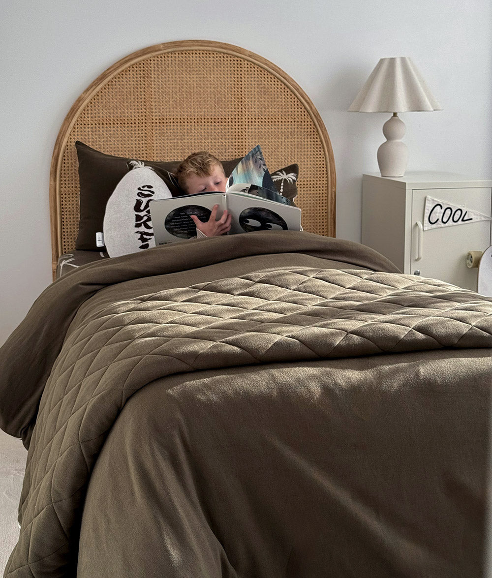 Olive Surfing Palm bedding styled on a single bed.