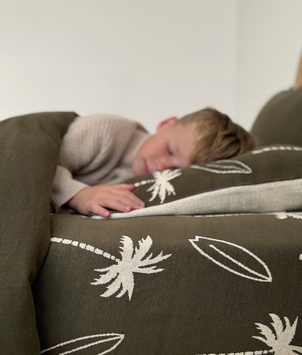 Child sleeping with Olive Surfing Palm reversible pillowcase and quilt.
