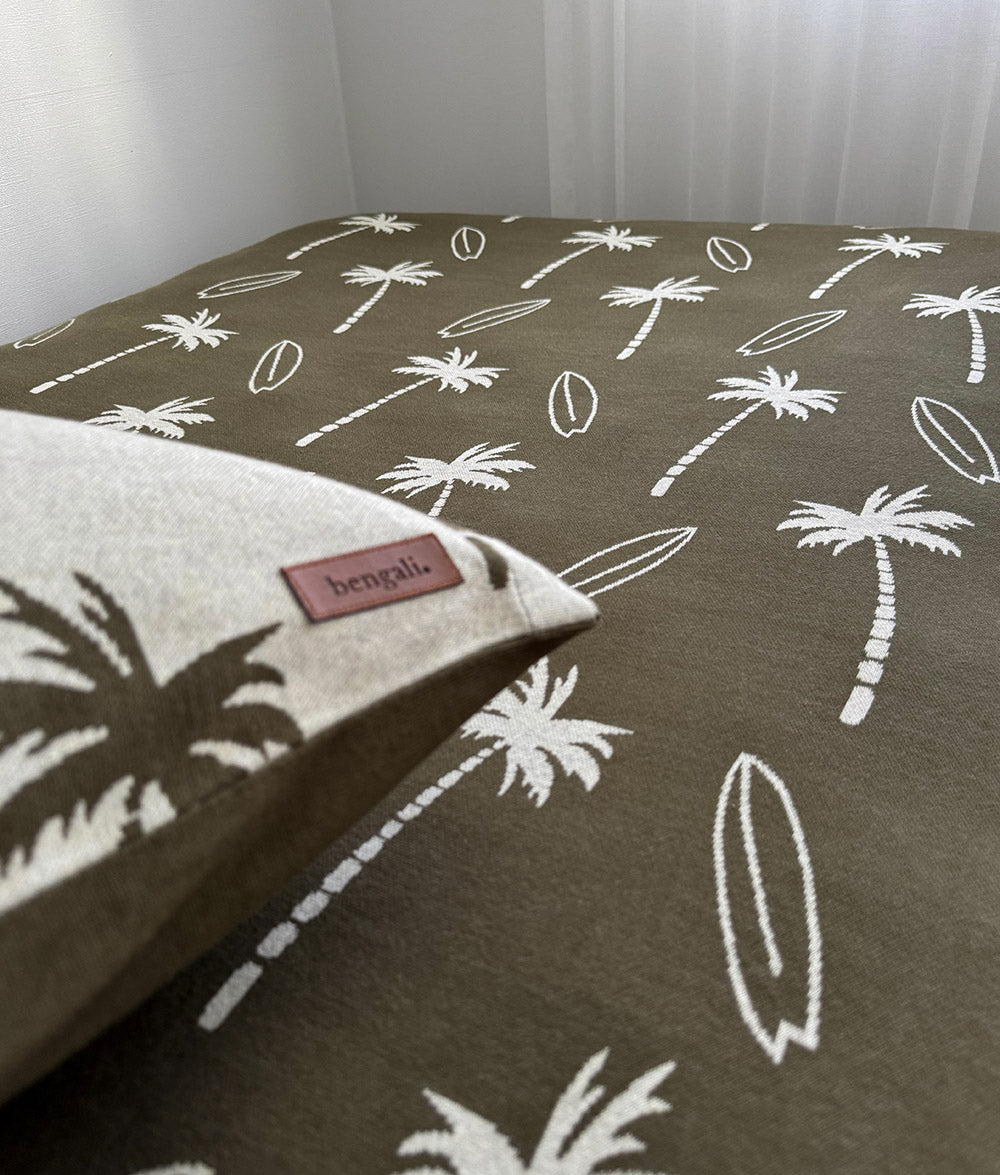 Close-up of Olive Surfing Palm jersey cotton fitted sheet with Bengali leather label.