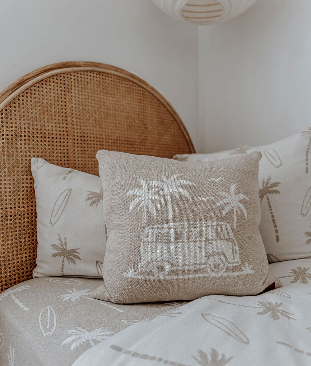 Decorative pillows with tropical designs on a bed with a wicker headboard.