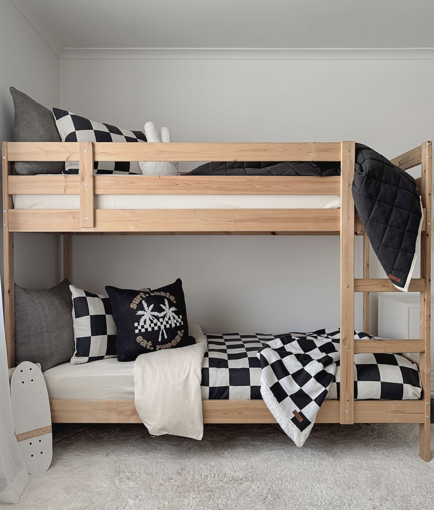Wooden bunk bed with checkered bedding and decorative pillows in a room.