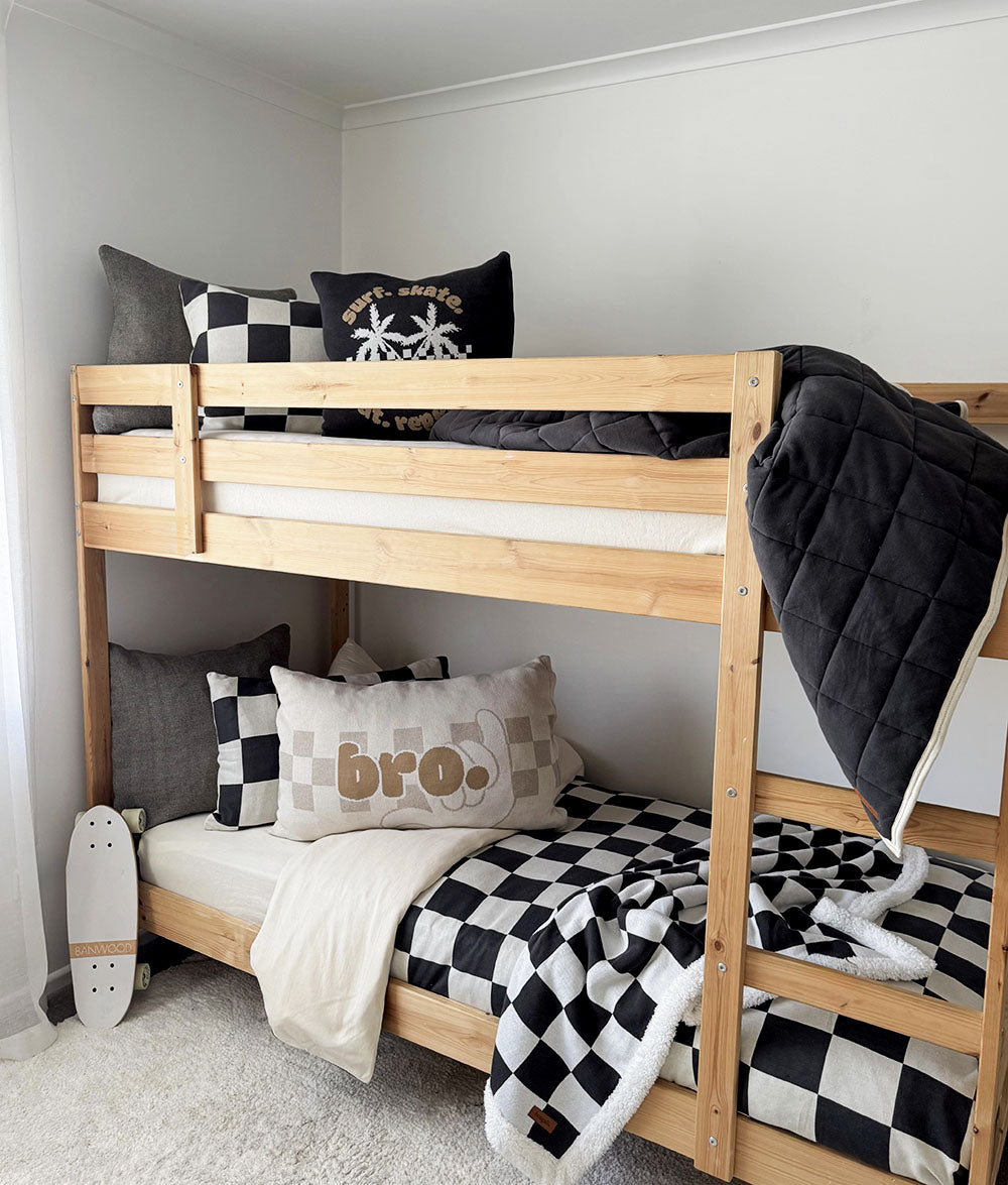 Wooden bunk bed with checkered and plaid bedding in a room setting