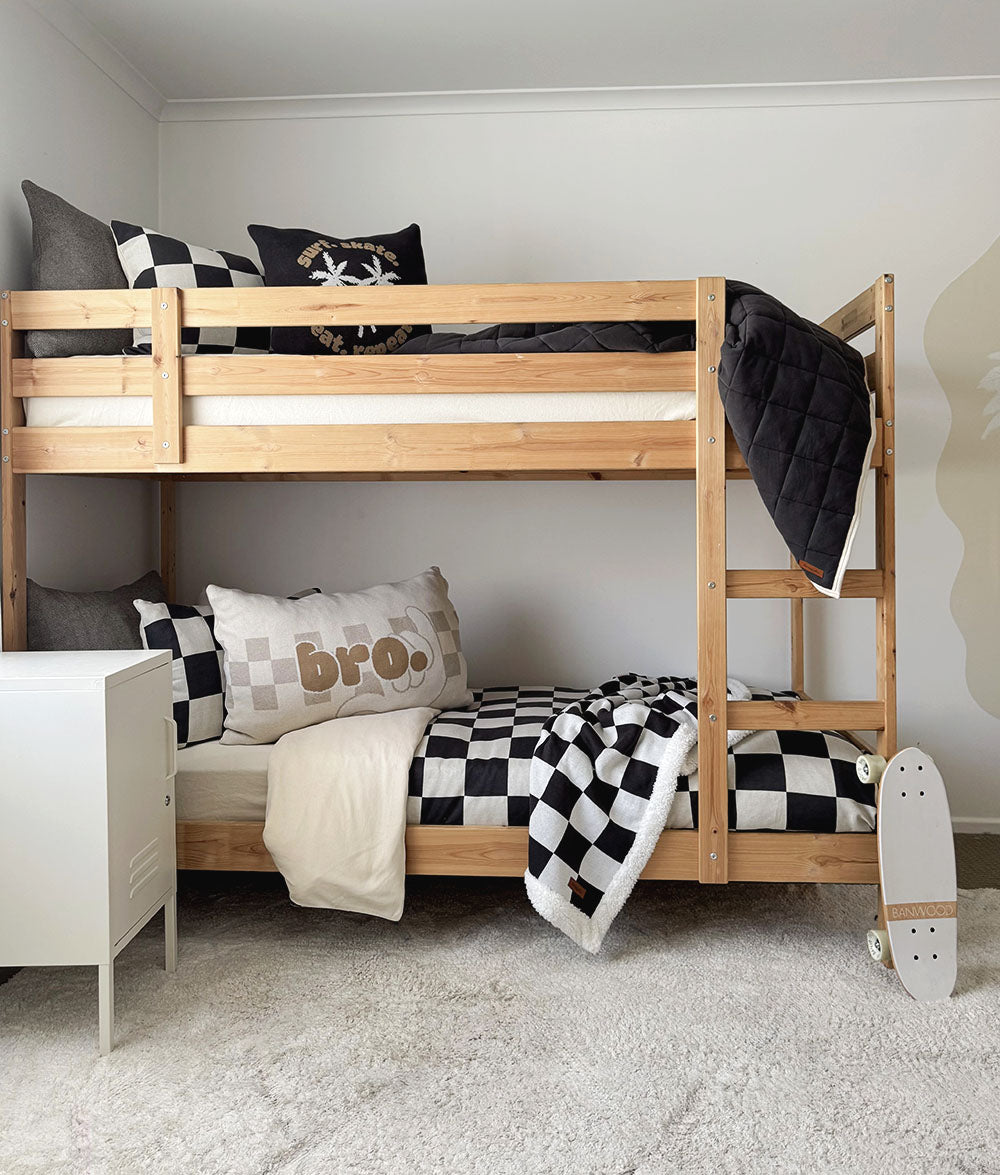 Wooden bunk bed with checkered bedding and pillows in a room setting.