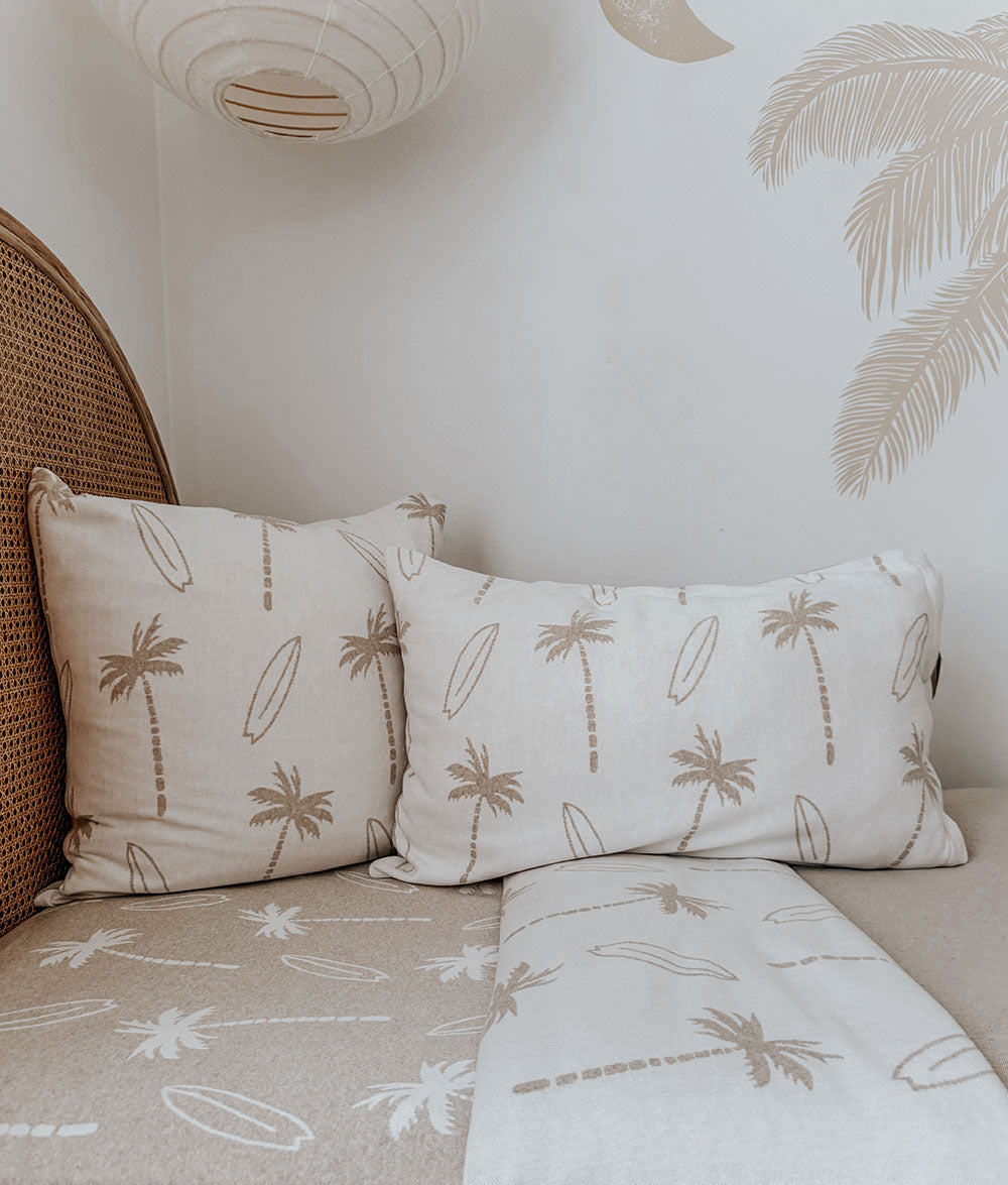 Pillowcases with palm tree design on a bed with matching bedding.